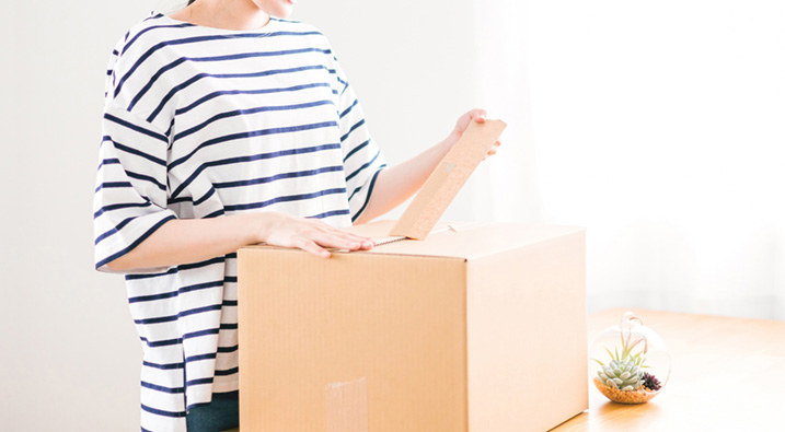 宅配の荷物を開ける女性の画像