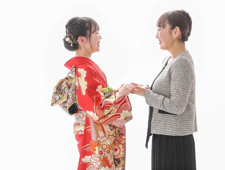振袖を着た女性とその母親が向き合い喜び合う様子の画像