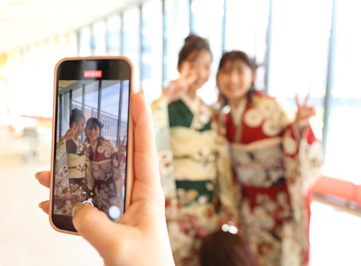 振袖姿の女性二人をスマホで撮影する様子